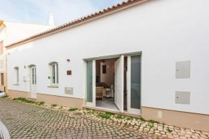 een wit huis met schuifdeuren op een straat bij Casa elegante em Vila tranquila in Barão de São Miguel