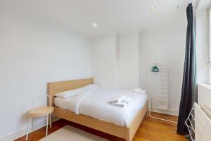 a bedroom with a bed with white sheets and a window at Cozy 2 Bedroom Flat in Cambridge Heath in London