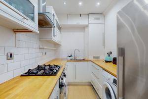 a white kitchen with a stove and a sink at Cozy 2 Bedroom Flat in Cambridge Heath in London