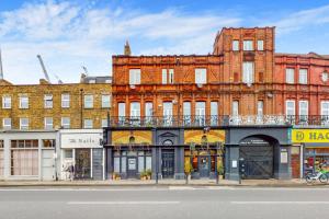 a large brick building with a balcony on a street at Cozy 2 Bedroom Flat in Cambridge Heath in London