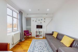 a living room with a couch and a tv at Cozy 2 Bedroom Flat in Cambridge Heath in London
