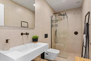 La salle de bains est pourvue d'un lavabo blanc et d'une douche. dans l'établissement Villa Salty, à San Javier