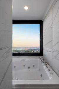 La salle de bains est pourvue d'une baignoire et d'une grande fenêtre. dans l'établissement LUNA RESIDENCE, à Altınova