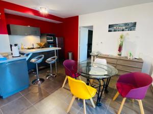 una cucina con tavolo in vetro e alcune sedie di Appartement T2 cosy à Rodez a Rodez