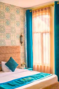 a bedroom with a bed and a window with blue curtains at Sahil Inn Baku Hotel Formula 1 View in Baku