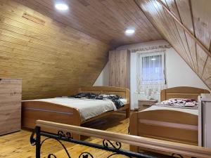 two beds in a room with wooden walls at Vikendica Martinović in Divčibare