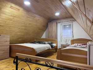 zwei Betten in einem Zimmer mit Holzwänden in der Unterkunft Vikendica Martinović in Divčibare
