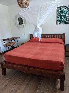 um quarto com uma cama com um edredão vermelho em Coquette villa avec piscine proche des plages em Sans Pareil