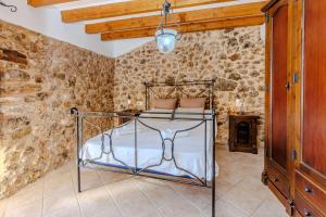 1 dormitorio con 1 cama en una habitación con paredes de piedra en Villa Can Abrines, en Lloseta