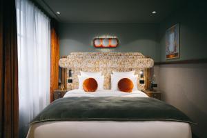 a bedroom with a large bed with orange pillows at 1,75 Paris La Sève in Paris