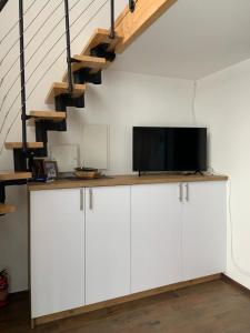 a living room with white cabinets with a tv and a staircase at Domki Blisko Nieba I in Wisła