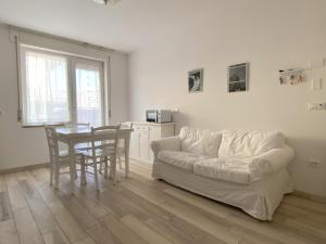 a living room with a white couch and a table at WoodenKey Asiago grazioso appartamento in centro in Asiago