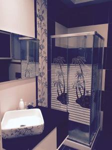 La salle de bains est pourvue d'un lavabo et d'une douche en verre. dans l'établissement Appartement pied dans l eau ,diamond bleu s+1, à Sousse