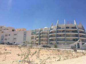 un gran edificio con coches estacionados frente a él en Appartement pied dans l eau ,diamond bleu s+1 en Sousse
