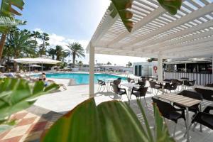 un patio con mesas y sillas y una piscina en One Bedroom with a pool, near Playa Chica, en Puerto del Carmen