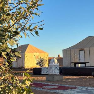a group of tents with a bench in front of it at Merzouga Desert Campsite &Activities in Merzouga