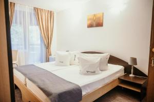 Schlafzimmer mit einem Bett mit weißer Bettwäsche und Kissen in der Unterkunft Valea lui Liman in Tomeşti
