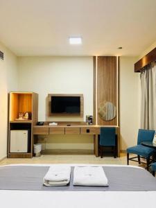 een slaapkamer met een bed en een bureau met een televisie bij Mermaid Beach Hotel LLC in Ajman 