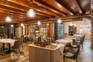 バッサーノ・デル・グラッパにあるHotel Alla Corte SPA & Wellness Relaxの白いテーブルと椅子、照明が備わるレストラン
