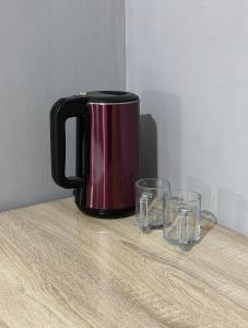 une cafetière noire posée sur une table avec deux verres dans l'établissement Holiday house Bishkek, à Bishkek