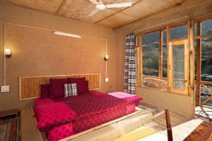1 dormitorio con 1 cama roja en una habitación con ventanas en Living Good - A Himalayan Boutique Stay en Gushaini