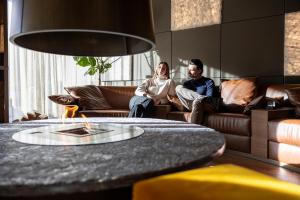 a man and woman sitting on a couch in a living room at Hotel Splendid in Madonna di Campiglio
