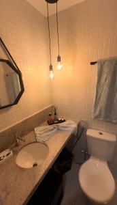 La salle de bains est pourvue de toilettes blanches et d'un lavabo. dans l'établissement Studio na Orla, à Salvador