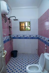 a bathroom with a toilet and red and blue tiles at Studio meublé R1 in Lomé