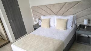 ein Schlafzimmer mit einem großen Bett mit weißer Bettwäsche und Kissen in der Unterkunft HOTEL LE FALEP in Anapoima