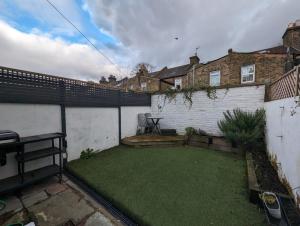 een kleine achtertuin met een hek en een grasveld bij Lux 3 Bed London House - Garden in Londen