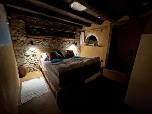 a bedroom with a bed and a stone wall at Hobití domček in Banský Studenec