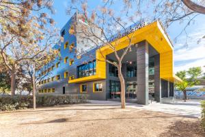un edificio de oficinas con fachada amarilla en Hotel Villa Universitaria, en San Vicente del Raspeig