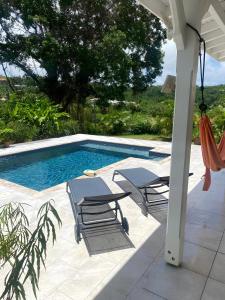 uma piscina com 2 espreguiçadeiras e um baloiço em Coquette villa avec piscine proche des plages em Sans Pareil