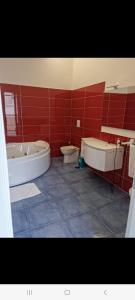 baño de azulejos rojos con 2 aseos y bañera en Suite FURORE, en Aversa