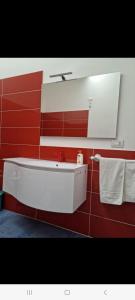 ein Badezimmer mit einem weißen Waschbecken und einer roten Wand in der Unterkunft Suite FURORE in Aversa