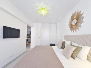 ein weißes Schlafzimmer mit einem Bett und einem Flachbild-TV in der Unterkunft TLN-0011 - Magnifique appartement proche centre-ville in Six-Fours-les-Plages