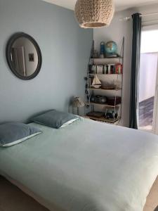 a bedroom with a large white bed and a mirror at Belle maison île de Ré avec piscine in Sainte-Marie-de-Ré