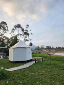 a small white tent in a field with a lake at Kayak Glamping in Pondokbungur