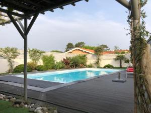 una piscina en un patio con terraza de madera en Villa avec piscine 12 personnes #0606 en Capbreton