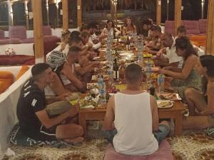 a group of people sitting around a long table at Life camp in Nuweiba
