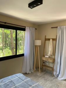 a bedroom with white curtains and a bed and a window at Bosque Libertad Loft in Mar Azul