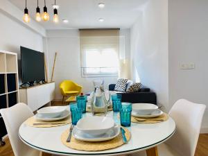 a white dining room table with plates and blue glasses at Apartamento HC13 - PUERTA PURCHENA in Almería