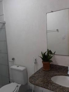 a bathroom with a toilet and a sink and a mirror at Apart Itapua in Salvador