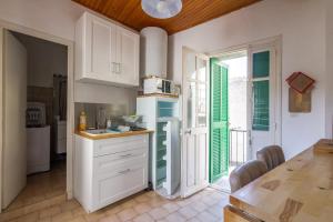 a kitchen with white cabinets and a table with a microwave at Di Mezzu - Proche plage et vue montagnes in Corbara