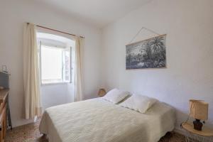 a white bedroom with a bed and a window at Di Mezzu - Proche plage et vue montagnes in Corbara