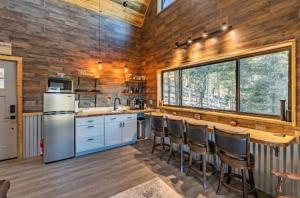 cocina con paredes de madera y encimera con taburetes en RidgeWalk Treehouse en Angel Fire