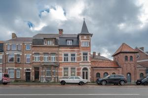 dos coches estacionados frente a un gran edificio de ladrillo en Villa Cézar - big house at the center of Bruges - free parking, en Brujas
