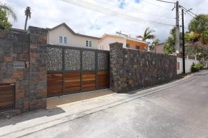 a brick fence with a wooden gate in front of a house at Meliyer cheerful 3 bedrooms villa at perebere in Pereybere