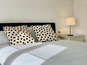 a bed with black and white pillows and a lamp at Apartamento HC13 - PUERTA PURCHENA in Almería