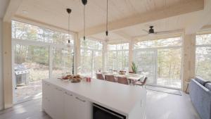 a kitchen with white cabinets and a dining room with windows at Chalet 24 - Modern peaceful retreat near Tremblant in La Conception